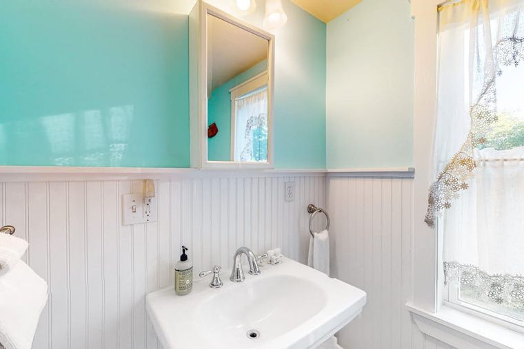 Full bathroom with aqua sea-glass walls, white beadboard wainscoting, and a pedestal sink.