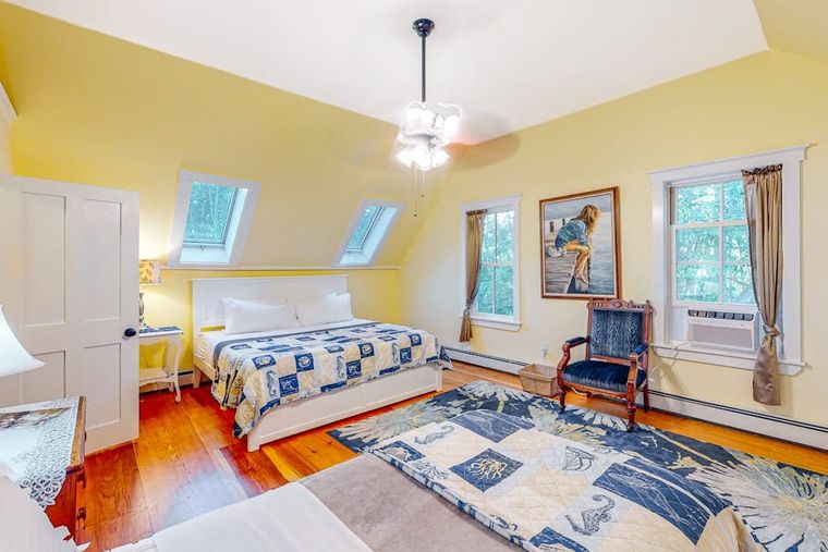 Buttercream upstairs bedroom with skylights, a king bed, and a nautical quilt.