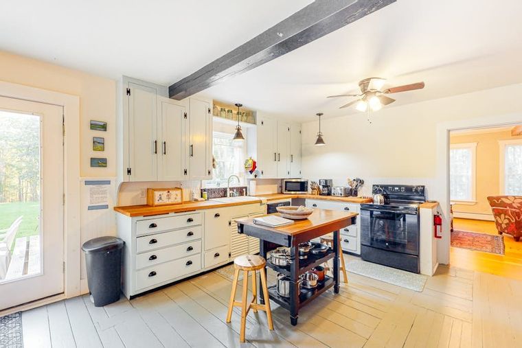 Bright farmhouse kitchen with sage cabinets, butcher-block counters, and a center island.