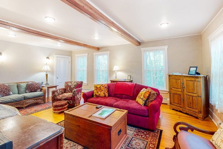 Second sitting room with exposed beams, two sofas, and warm pine floors.