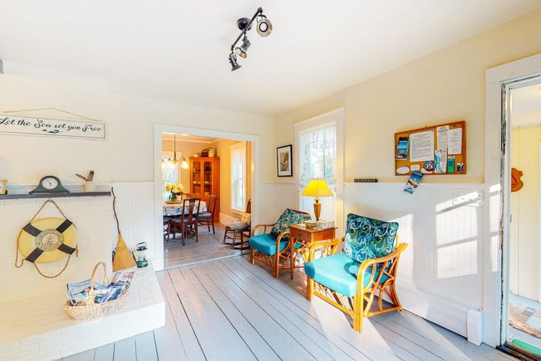 Enclosed sun porch with sea-glass blue rattan chairs and nautical decor by a white door.