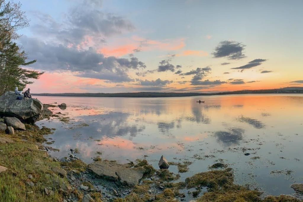 Pastel sunset over the calm cove with a canoe near the rocky shore, near Farmhouse on the Cove in Penobscot, Maine.